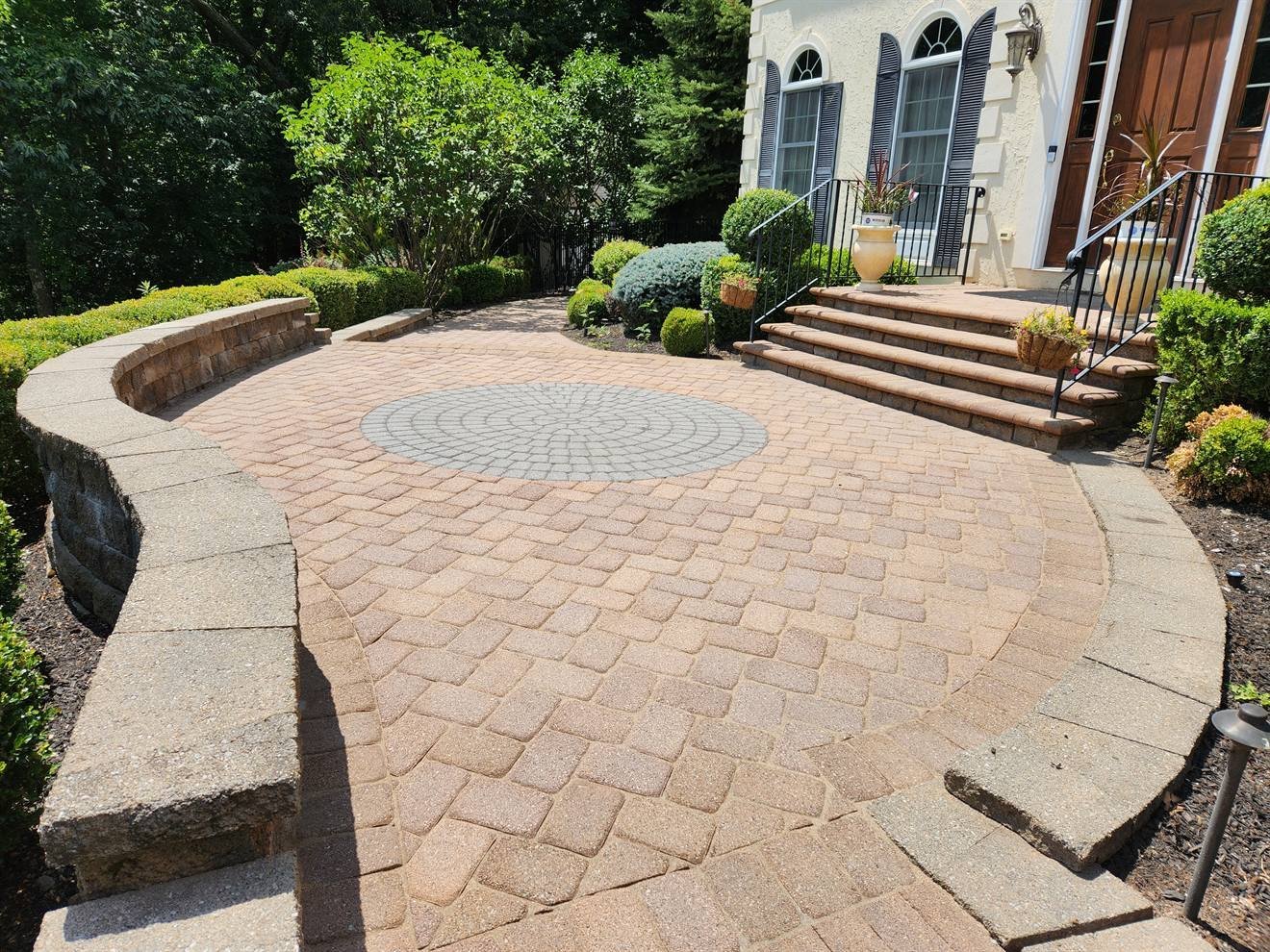 Curved paver entrance court with steps and planted borders
