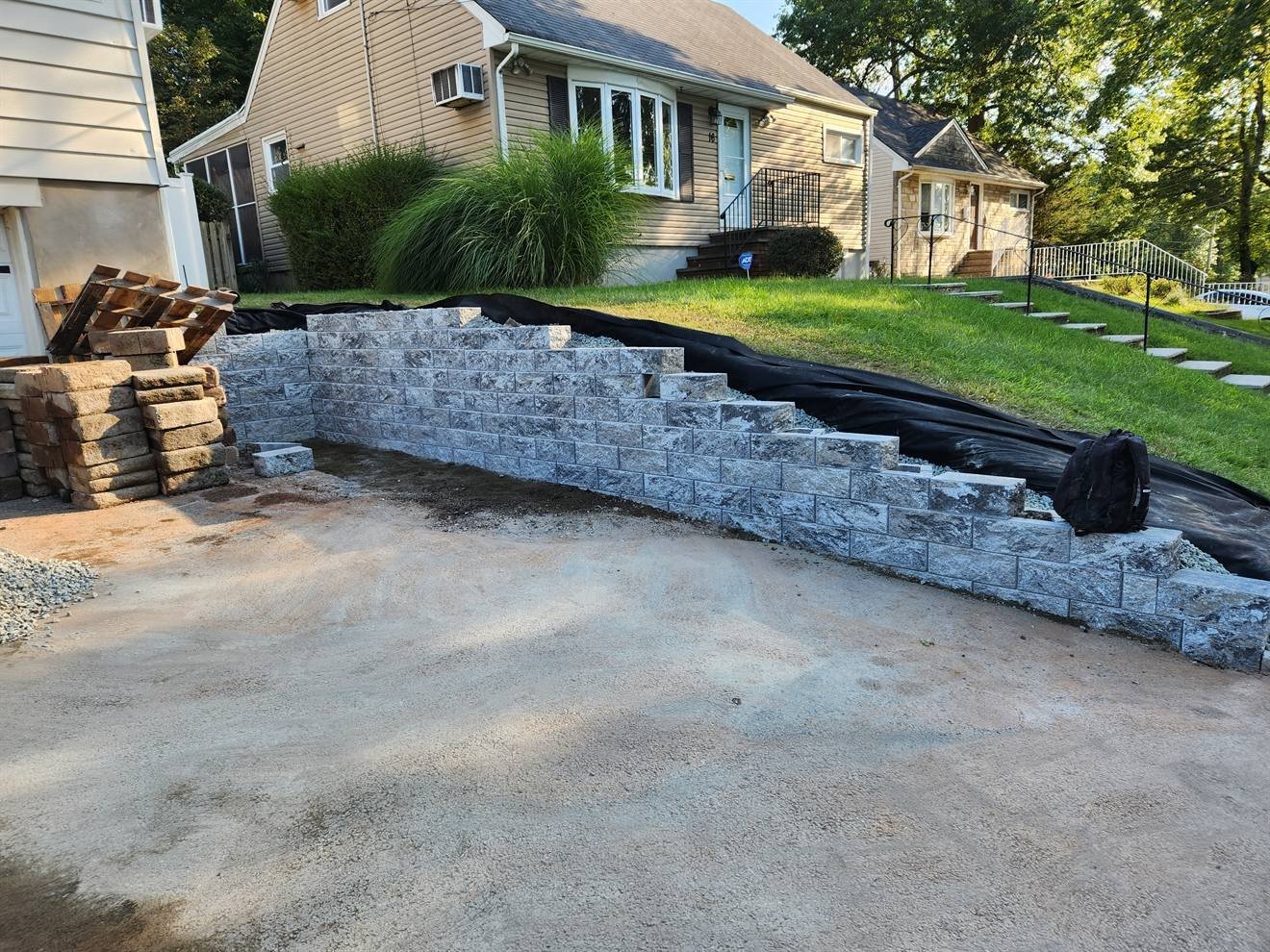 Tiered retaining wall under construction beside a driveway