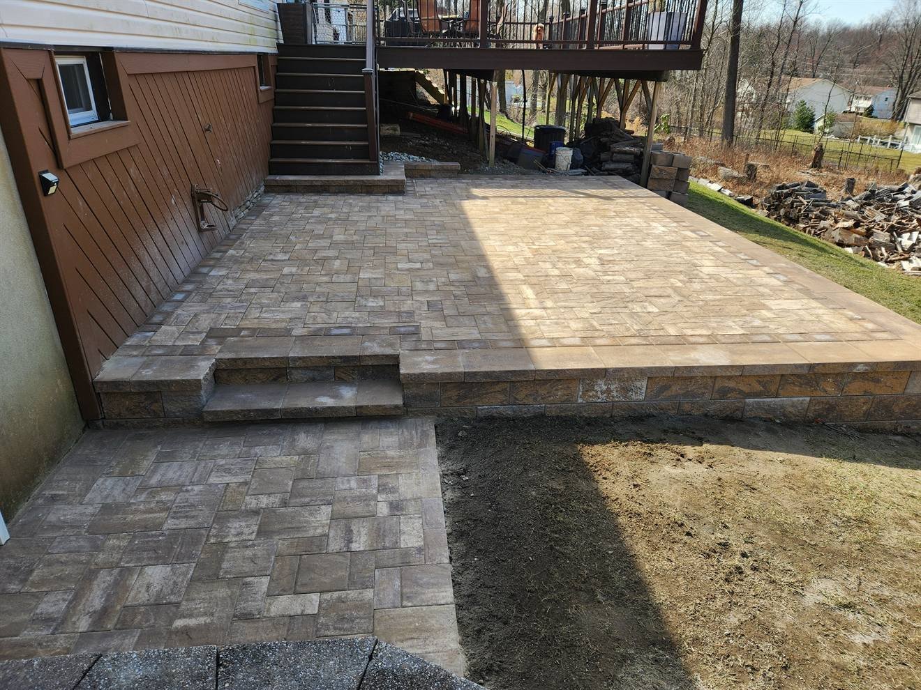 Raised backyard paver terrace with steps and retaining edge