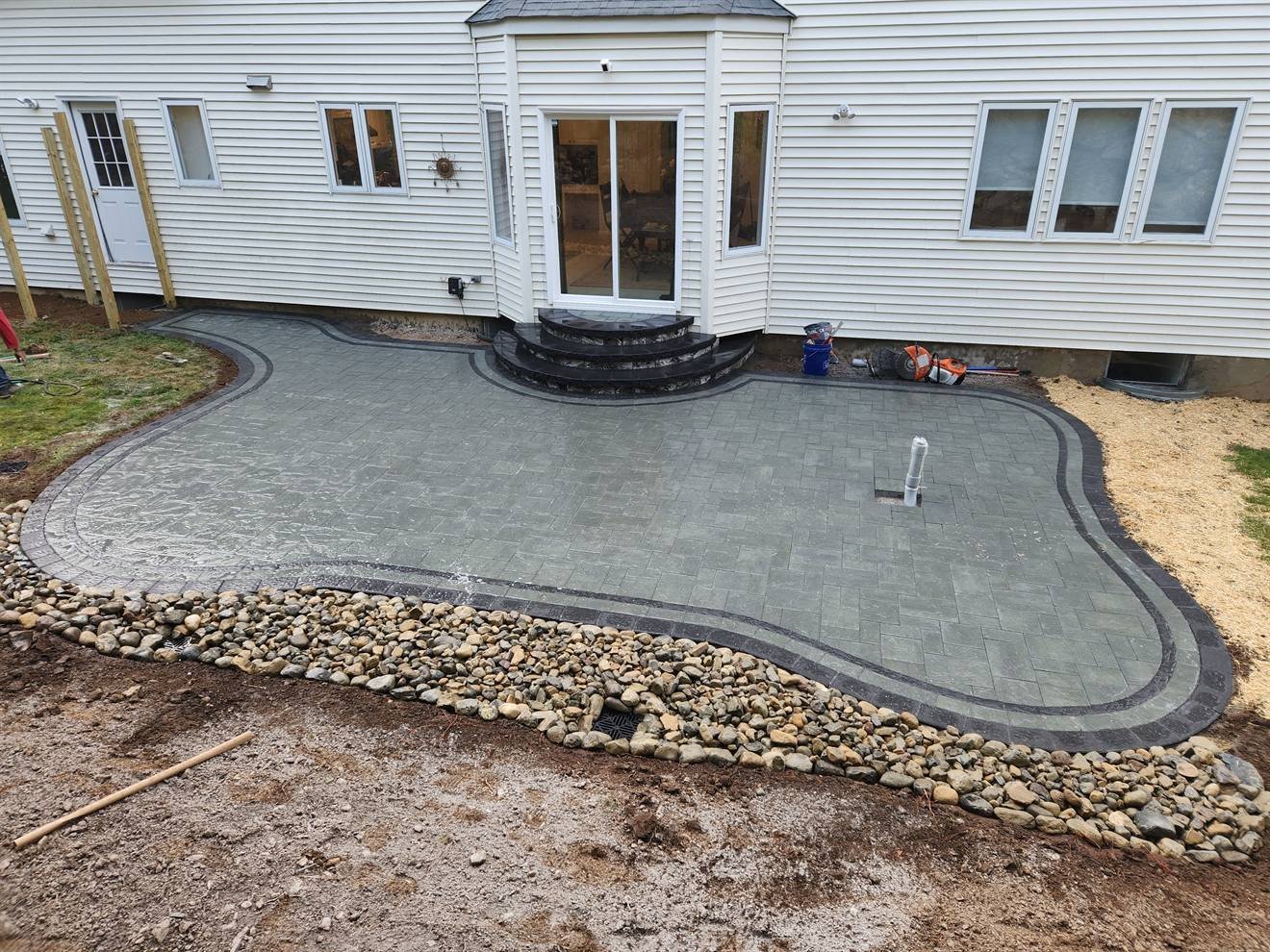 Wide view of the completed curved paver patio and drainage stone
