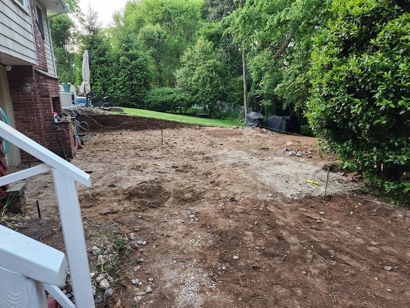 Cleared rear-yard area before a large patio installation