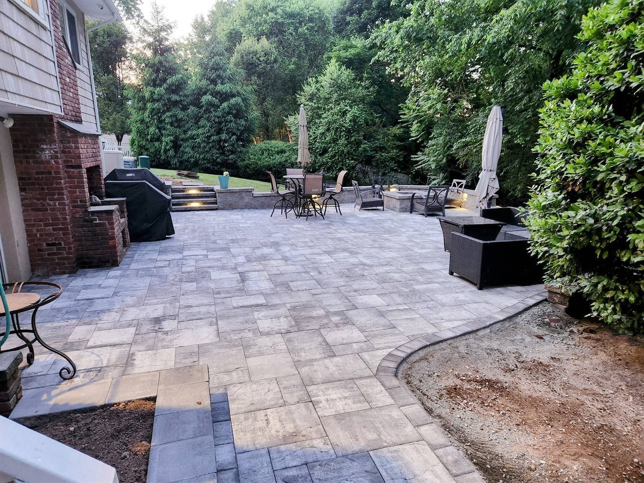 Furnished paver patio with illuminated steps and retaining walls