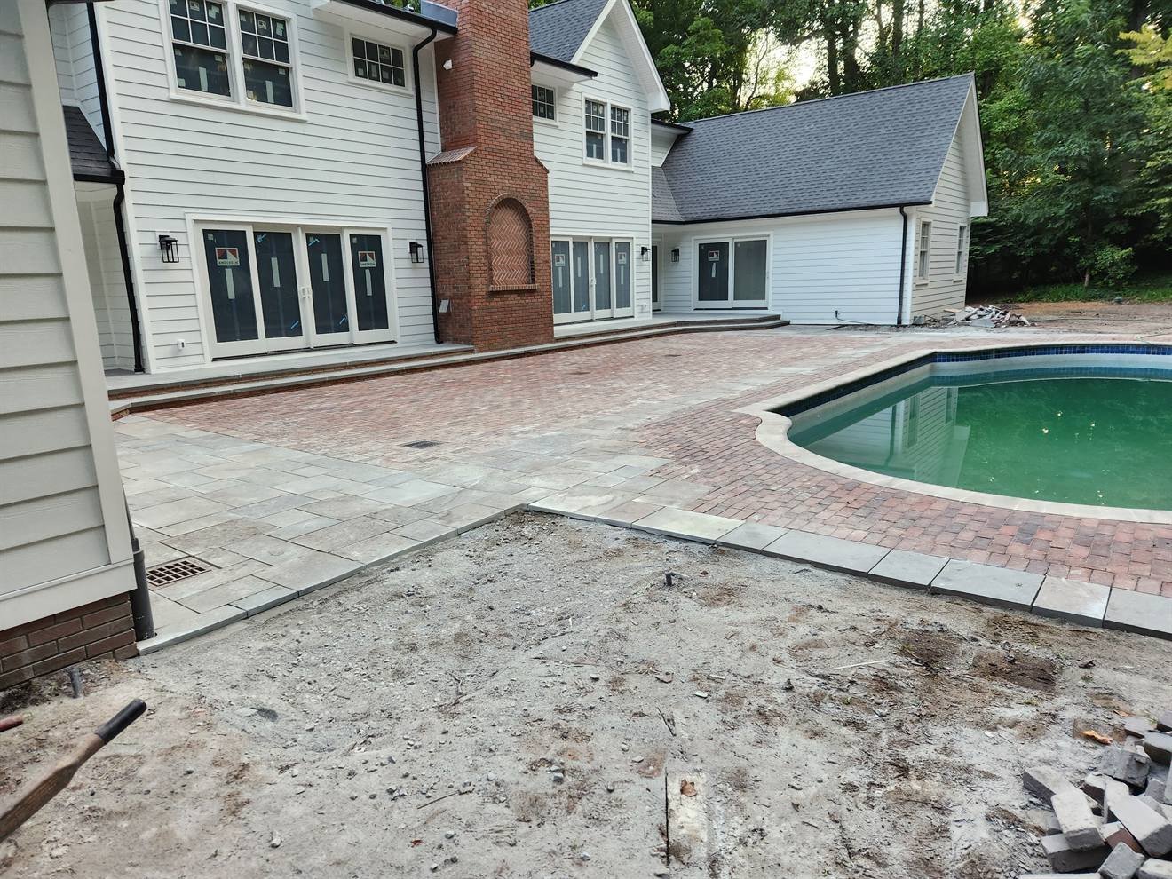 Completed paver patio surrounding a backyard pool